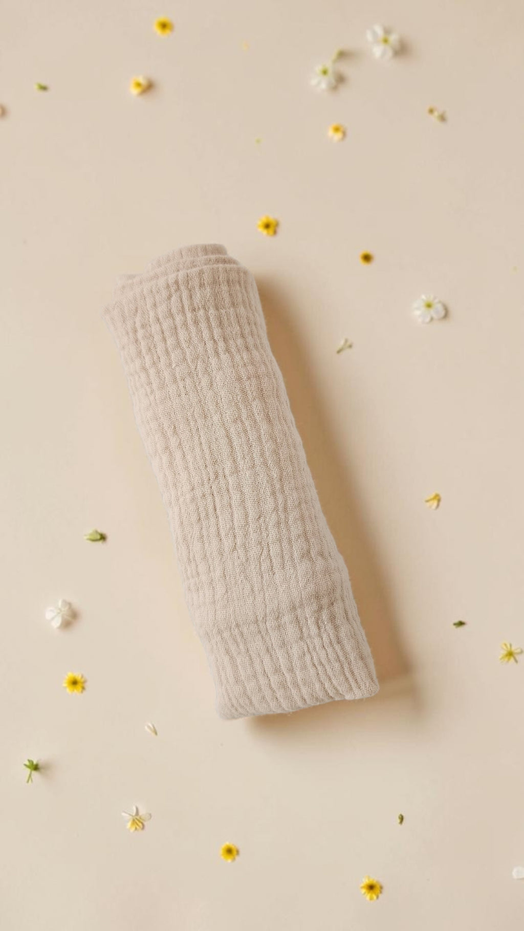 Cloudy Cotton beige organic muslin baby swaddle wrap with a soft textured finish on a floral background