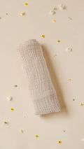 Cloudy Cotton beige organic muslin baby swaddle wrap with a soft textured finish on a floral background