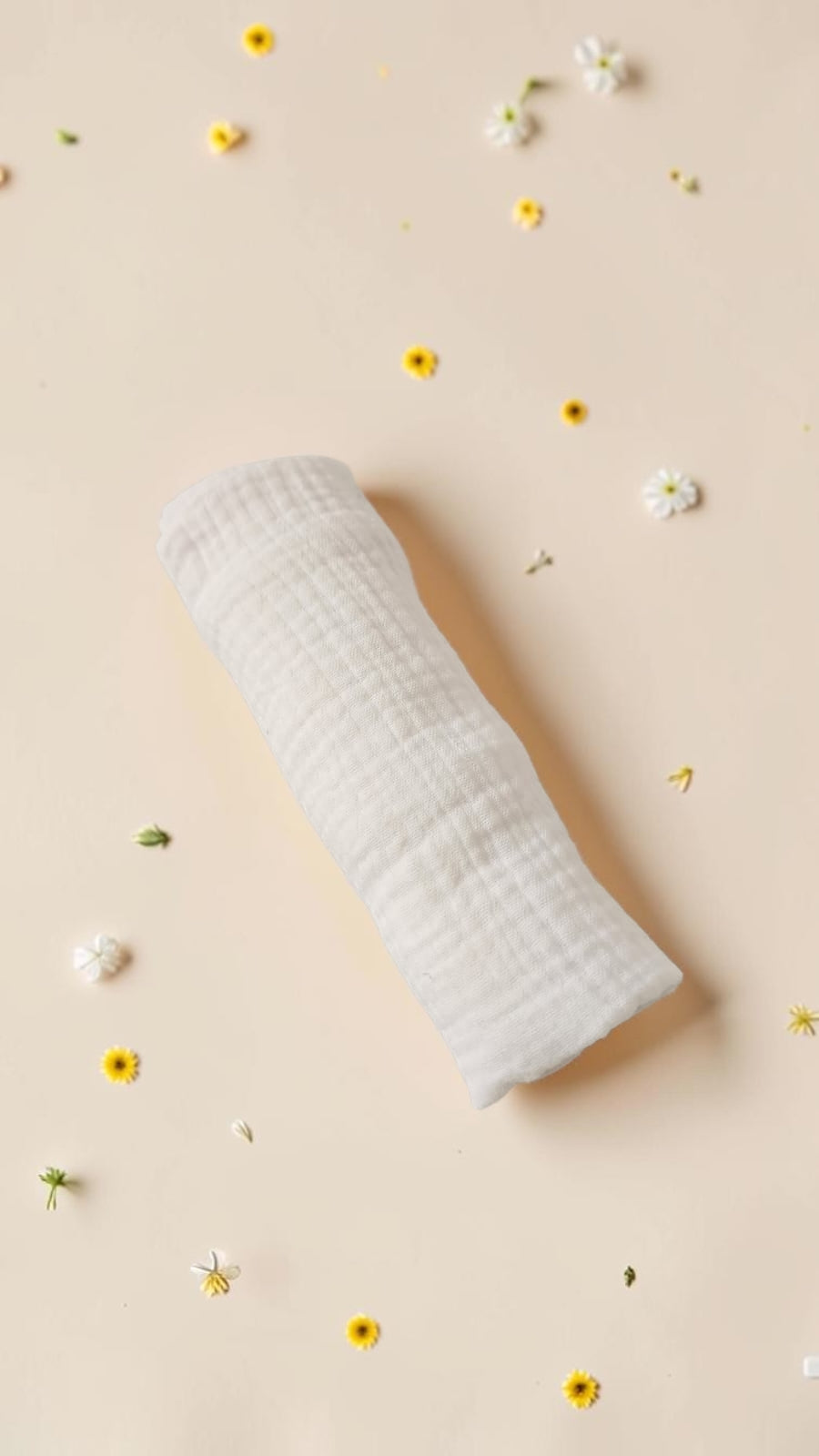 Cloudy Cotton off-white organic muslin swaddle blanket with a soft open-weave texture on a floral background.